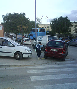 Un nio intenta pasar por la acera llena de coches de al lado del colegio. (Foto: Flix Garca)