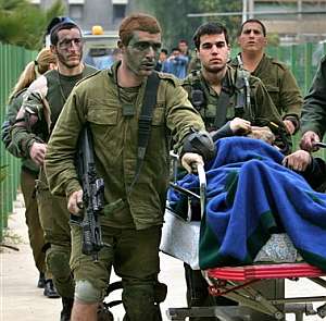 Varios soldados israeles trasladan a un militar herido en camilla. (Foto: AP)