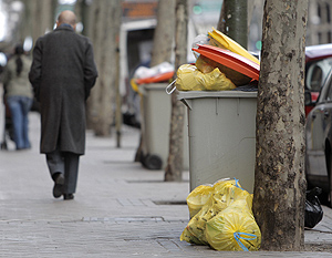 Un hombre camina junto a unos contenedores repletos de basura en Madrid. (Foto: EFE)