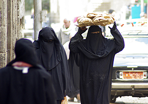 Una mujer camina con un cargamento de hogazas en la cabeza tras salir de una panadería. (Foto: EFE)