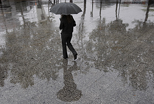 Una mujer transita bajo la lluvia. (Foto: EFE)