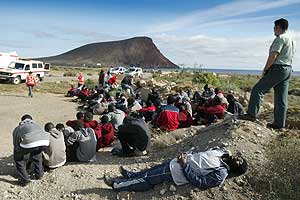 Un grupo de inmigrantes descansa tras llegar a bordo de un cayuco a la playa de La Tejita, en el municipio de Granadilla, al sur de Tenerife. (Foto: EFE)