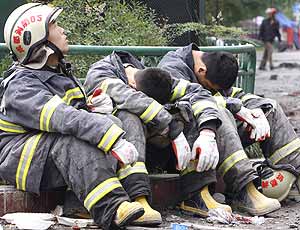 Tres bomberos desolados y exhaustos en Dujiangyan. (Foto: REUTERS)