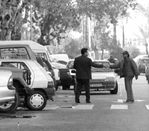Un aparcacoches ilegal negocia con un cliente. (Foto: Benito Pajares).