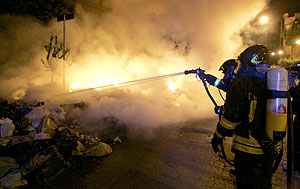 Unos bomberos extinguen las llamas que salen de una pila de basura en Npoles (Foto: EFE)