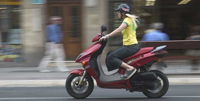 Una joven circula por la calle con su ciclomotor. (Foto: P. Vias)