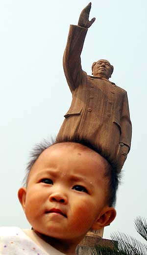 Un bebe chino bajo una estatua de Mao Zedong. (Foto: AP)
