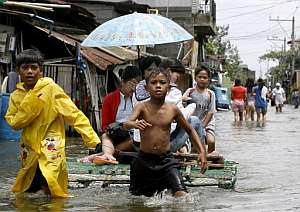 Dos nios filipinos tiran de una balsa improvisada por una calle inundada en la ciudad de Malabon, al norte de Manila. (Foto: EFE)