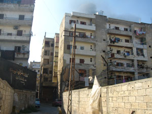 Una columna de humo asciende tras la entrada al barrio de Bab al Tebaneh, desierto por los combates.