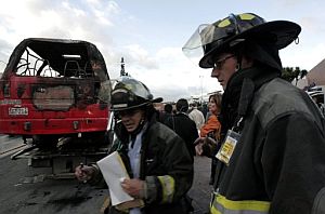 Los bomberos inspeccionan uno de los vehculos incendiados. (Foto: EFE)