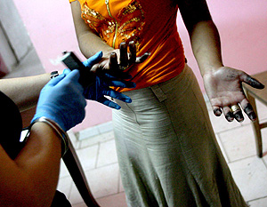 Una agente toma las huellas dactilares de una joven de etnia gitana en Npoles. (Foto: EFE)