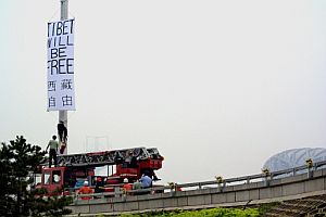 Los bomberos intentan descolgar una pancarta con el lema 'Tbet ser libre'. (Foto: AFP)