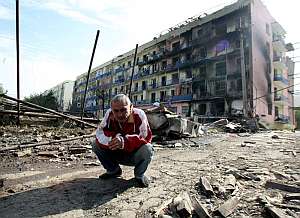 Un hombre se agacha delante de un edificio daado por los bombardeos rusos en la ciudad de Gori (Georgia). (Foto: EFE)