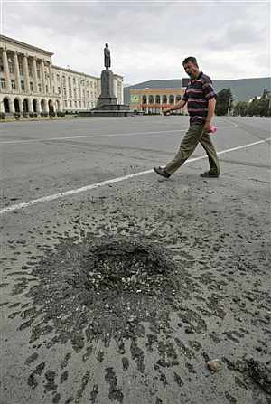 Un georgiano pasa junto a un agujero provocado por una granada cerca del monumento a Stalin en la ciudad de Gori. (Foto: AP)