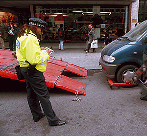 Una polica municipal poniendo una multa a un vehculo mal estacionado antes de que se lo lleve la gra.