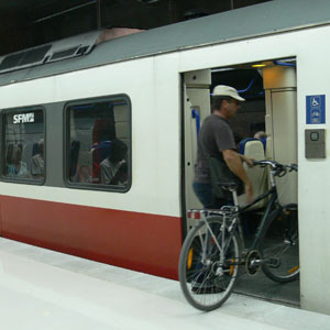 Un hombre entra en un vagn de tren con su bicicleta.