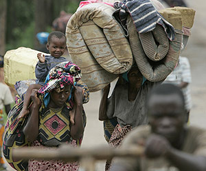 Varios congoleos cargados de sus pertenencias huyen de los enfrentamientos. (Foto: Karel Prinsloo)