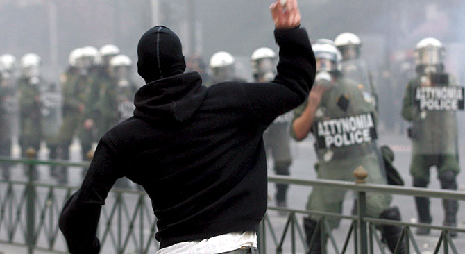 Un joven lanza un objeto a la policía en uno de los enfrentamientos. (Foto: EFE).