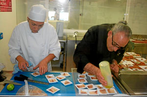 Dos de los cocineros de la empresa preparan tapas de 'llampuga fumada'. (Foto: M. Salietti)