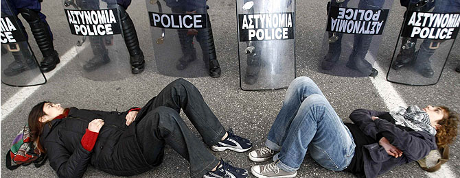 Dos manifestantes, tumbadas enfrente de la Polica en Atenas. (Foto: REUTERS)