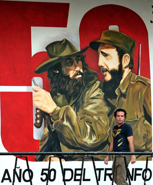 Un hombre camina en La Habana junto a un cartel conmemorativo con la imagen de Fidel y el comandante Camilo Cienfuegos. (Foto: EFE)