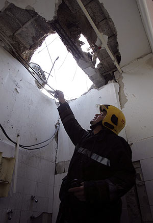Un bombero israelí observa el agujero producido por uno de los cohetes. (Foto: REUTERS)