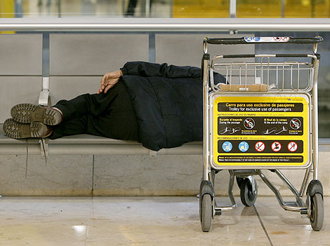 Un pasajero duerme en la T-1del aeropuerto de Barajas. (Foto: Alberto di Lolli)