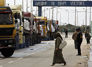 Una mujer cruza la calle delante de una fila de camiones con ayuda humanitaria en la frontera egipcia de Rafah. (Foto: AFP)