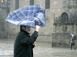 Un hombre se protege contra el viento y la lluvia con un paraguas en Santiago de Compostela. | EFE