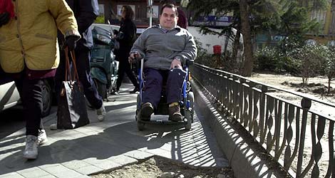 Un hombre en silla de ruedas intenta superar los baches de la acera. | Jos Ayma