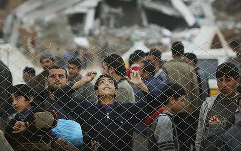 Un grupo de nios palestinos esperan tras una alambrada para recibir comida, al norte de la Franja. | AP