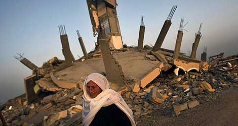 Una mujer pasa por delante de una casa destrozada durante la ofensiva militar. | AFP