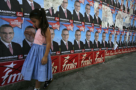 Una nia salvadorea, ante carteles electorales de Funes. | AP