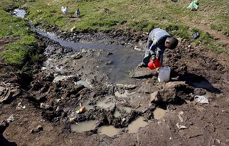 Un nio llena un bidn con agua de un charco en las afueras de Nairobi. | Efe