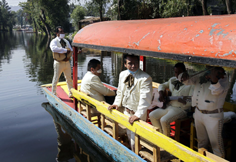 Un grupo de mariachis, con mscara, por los canales de Xochimilco. | Reuters