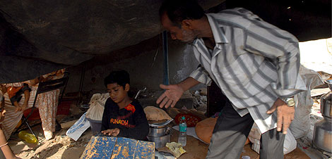 Azharuddin Ismail M. Shaij, a la izquierda, habla con su padre en una chabola derribada. | Efe