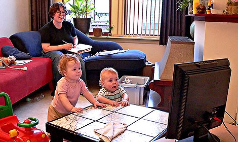 Niños delante de la televisión junto a su madre.