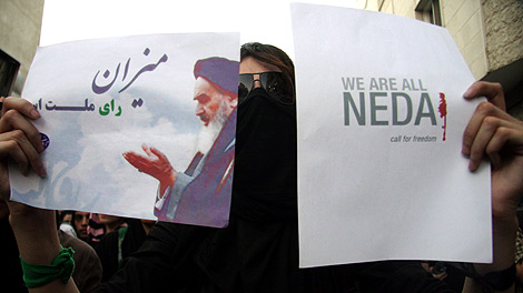 Una mujer iran sostiene un cartel con la foto de Jameini y otro en apoyo a Neda. | Reuters