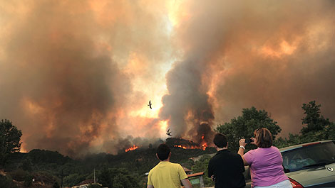 Vecinos de Mombeltrn realizan fotos del incendio desatado en la localidad. | AFP