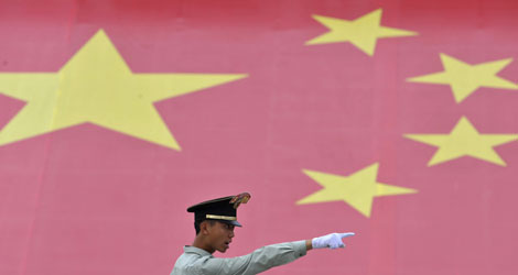 Un polica chino gesticula delante de la bandera nacional en un cuartel militar de Pekn. | Reuters