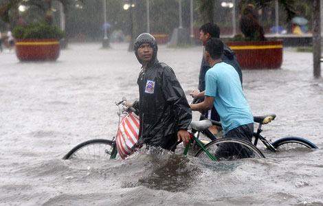 Dos hombres intentan cruzar una calle inundada en Manila. | Efe
