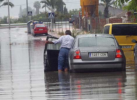 Un hombre junto a su vehculo en una calle inundada de la capital murciana. | Efe