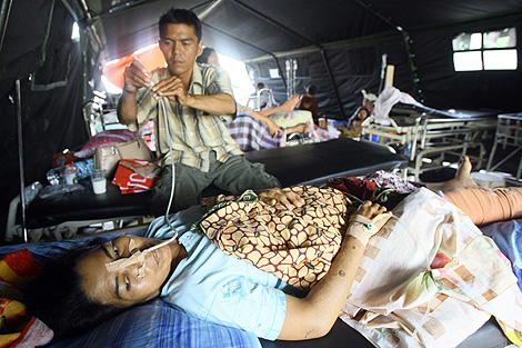Una mujer superviviente del sesmo es atendida por su esposo en Padang. | Efe