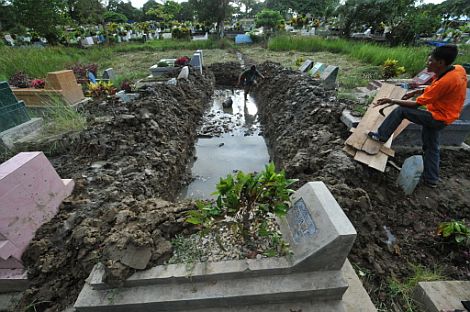 Dos hombres preparan una fosa para enterrar los cadveres en Padang. | Afp