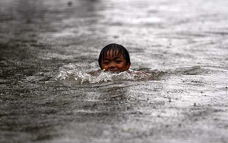 Un niño nada por las calles inundadas de la localidad de Victoria. | Efe