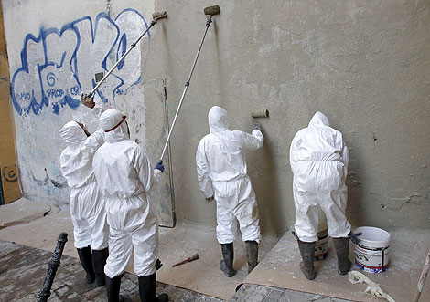 Grupo de grafiteros limpiando la pared.| Efe
