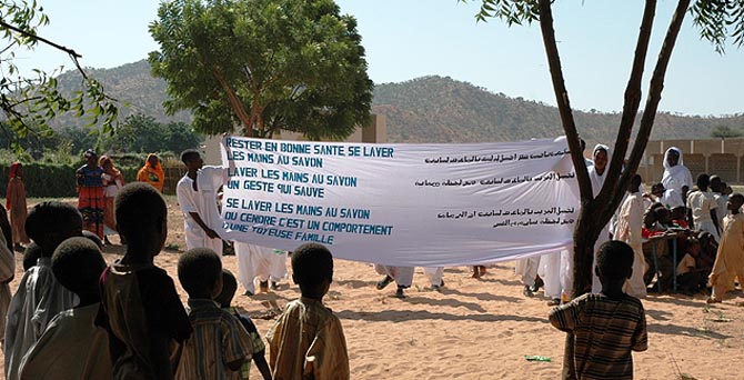 Los promotores de higiene de Intermn Oxfam portando una pancarta con consejos, en francs y rabe.