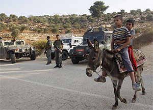 Unos nios palestinos pasan junto a una patrulla israel en un asentamiento cercano a Nablus. (Foto: Reuters)