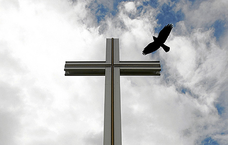Un cuervo vuela sobre la cruz papal del Parque Phoenix, cerca de Dubln. | Reuters