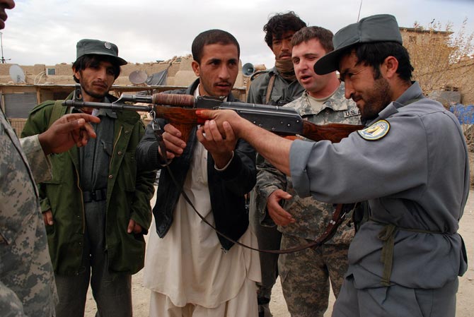 Un instructor estadounidense ensea a un polica afgano, con la ayuda de un traductor, cmo empuar un arma.| M. Bernab